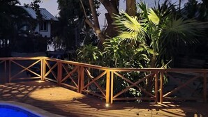 A pool area with a wooden deck and a metal railing. - Casa Coral 2 Bedroom Home by RedAwning (Roatan)