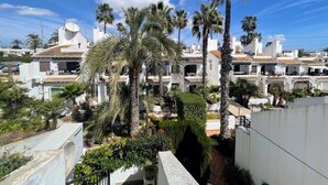 A residential area with white buildings, palm trees, and a clear blue sky. - Botanical 2 Bedroom Bungalow with Com Pool VM33 (Orihuela)