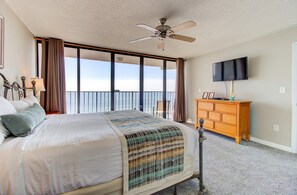 Une chambre d’hôtel équipée d’un lit, d’une commode, d’une télévision et d’un balcon avec vue sur l’océan.