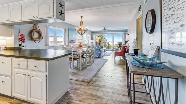 A spacious kitchen with white cabinetry, a central island, and a dining area with a chandelier. - N1 Amelia South 2 Bedroom Apts by RedAwning (Fernandina Beach)