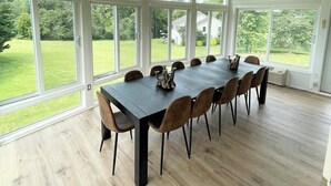 Une pièce spacieuse avec une grande table à manger, plusieurs chaises et un ventilateur de plafond.