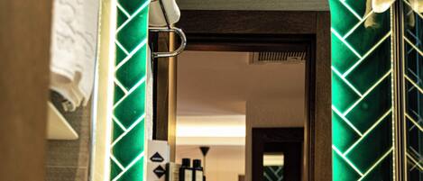 A bathroom with a white sink, a mirror, and a green patterned wall.