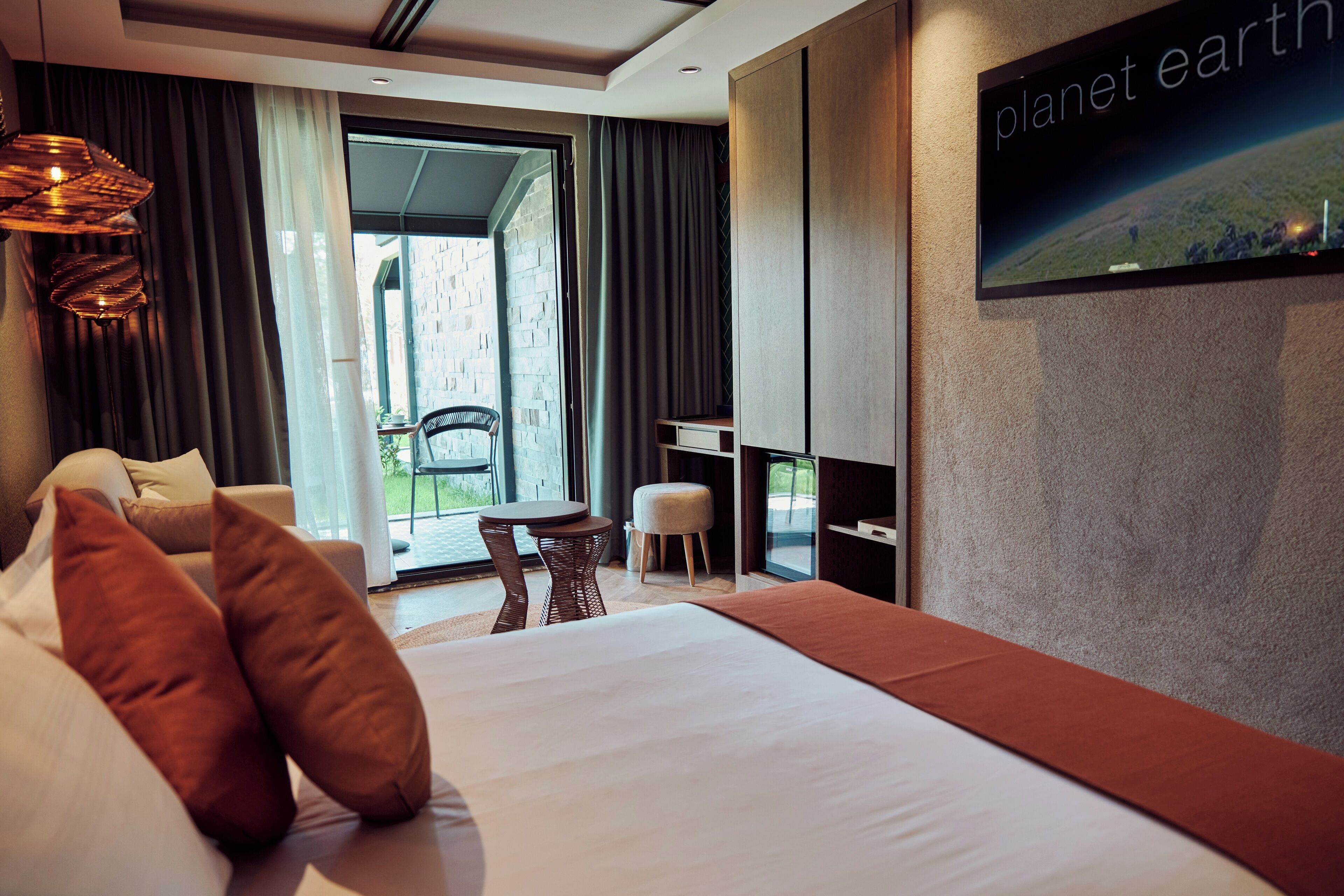 Une chambre d’hôtel moderne avec un grand lit, un téléviseur fixé au mur, une petite table et une chaise.
