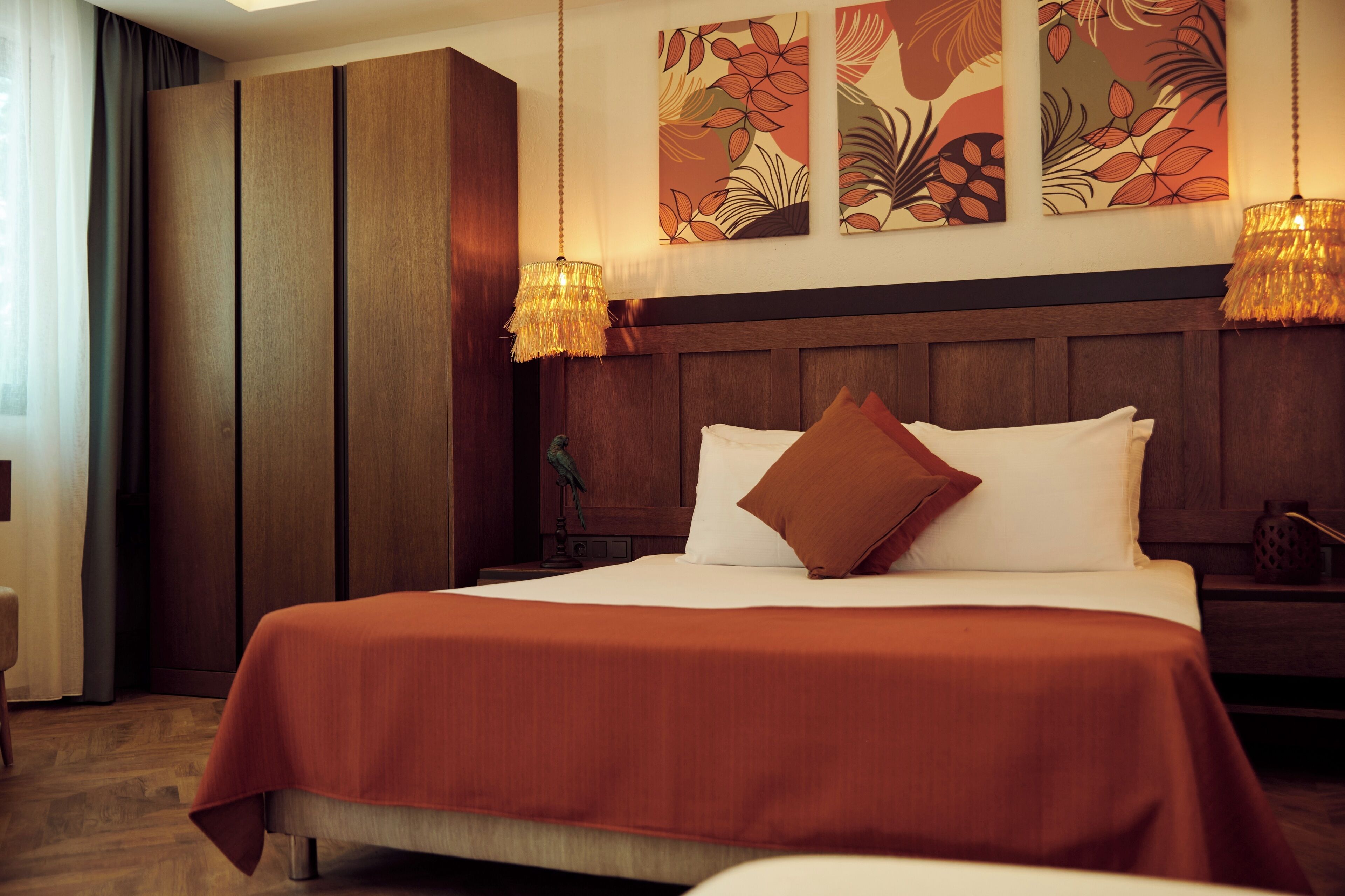 A hotel room with a large bed, wooden headboard, and two wall-mounted lamps.