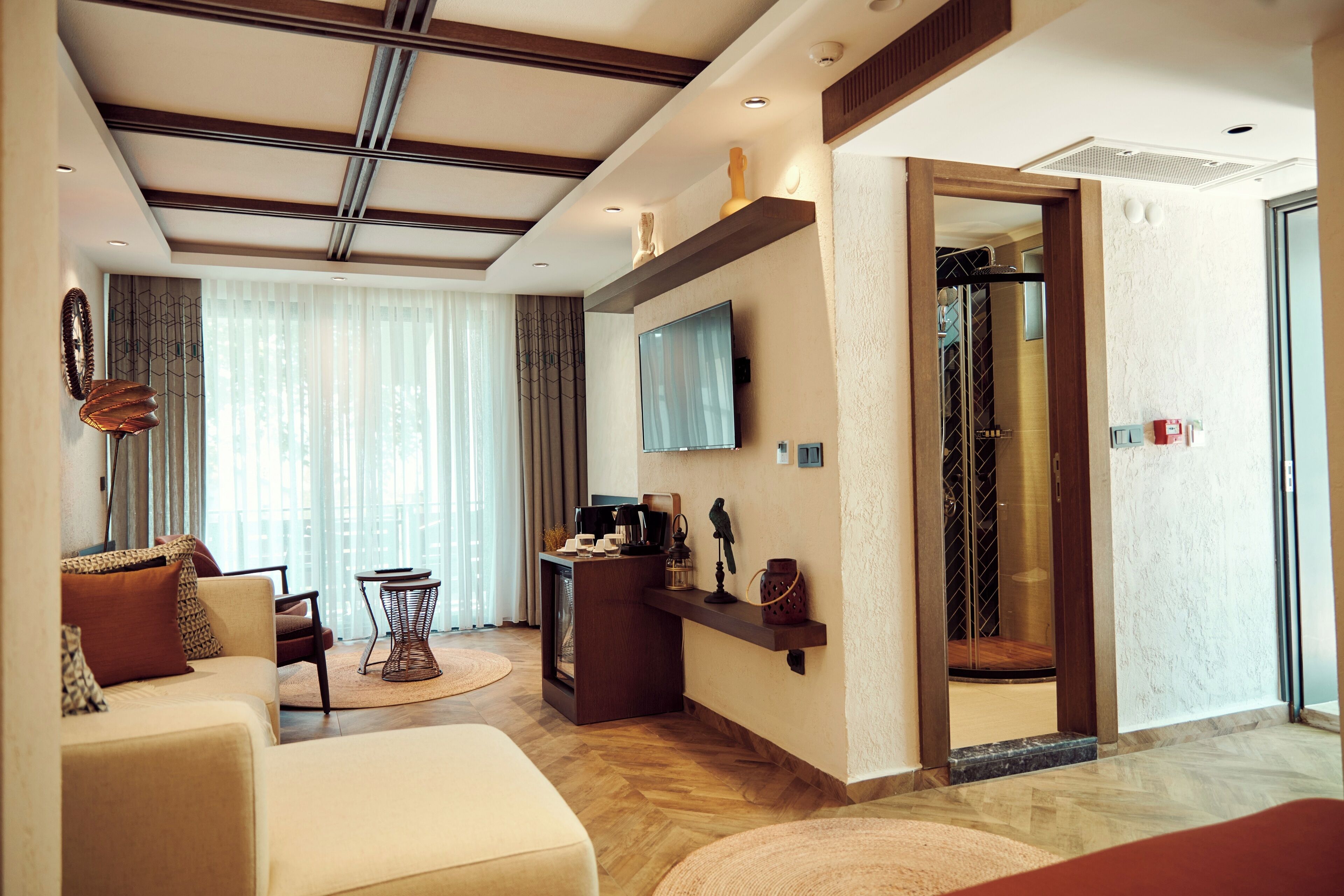 A modern hotel room with a sofa, coffee table, and a TV mounted on the wall.