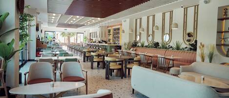 A spacious restaurant with high ceilings, modern furniture, and a variety of seating options.