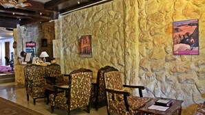 A lobby with stone wall decor, a Coca-Cola refrigerator, and patterned chairs.