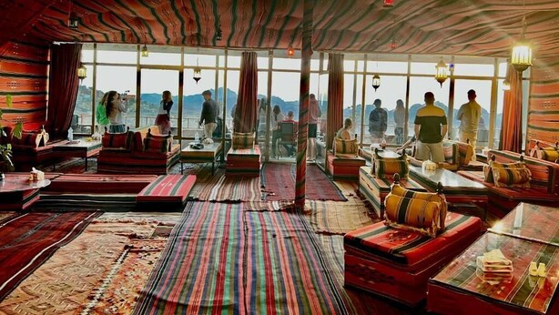 A room with large windows, striped rugs, and traditional seating.