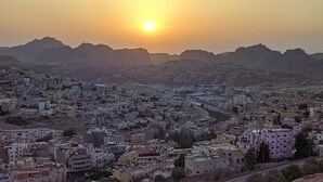 A cityscape with buildings and mountains during sunset.
