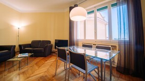 A modern living room with a glass dining table, leather sofa, and a floor lamp. - Elegant Apartment in the Center by Wonderful Italy (Sanremo)