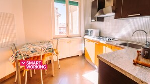 A kitchen with a dining table, chairs, a window, cabinets, and a countertop. - Elegant Apartment in the Center by Wonderful Italy (Sanremo)