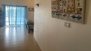 Ein geräumiges Wohnzimmer mit einem großen Gemälde einer Haflandschaft an der Wand, einer Bank und Blick durch eine Glastür.
