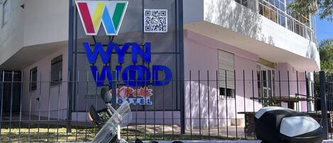 Una motocicleta Ducati blanca estacionada frente a un edificio con un letrero que dice 'WYNN KREW HOTEL'.