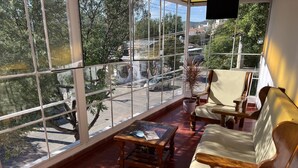 A sunlit room with large windows, wooden furniture, and a potted plant. - Hostel Wynwood Extreme (Villa Carlos Paz)