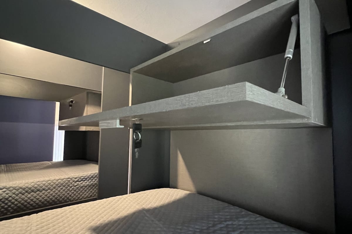 Une chambre compacte et moderne, équipée d’un lit superposé et d’un bureau escamotable.