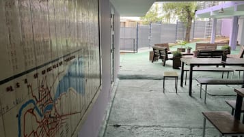 Quarto com um mapa grande na parede, piso de concreto e área de estar ao ar livre com mesas e cadeiras.