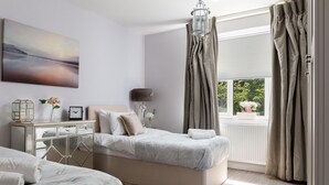 Une chambre à coucher avec un grand lit, des tables de chevet, un miroir et une fenêtre avec des rideaux.