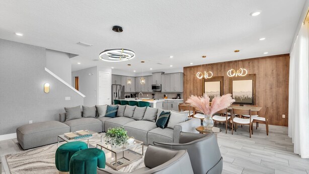 Un salon moderne avec un canapé d’angle, des poufs et une table basse.
