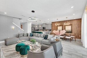 Uma sala de estar moderna com um sofá seccional, pufes e uma mesa de centro.