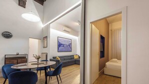 Un salon moderne avec un canapé, une table à manger et des chaises, un tableau au mur et un plancher en bois.