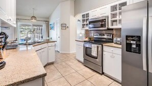 A modern kitchen with white cabinets, stainless steel appliances, and a granite countertop. - Entire home, Heated Pool, Lake view and Gazebo! (Riverview)