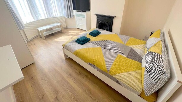 Een slaapkamer met een bed, een televisie, een open haard en een raam met gordijnen.