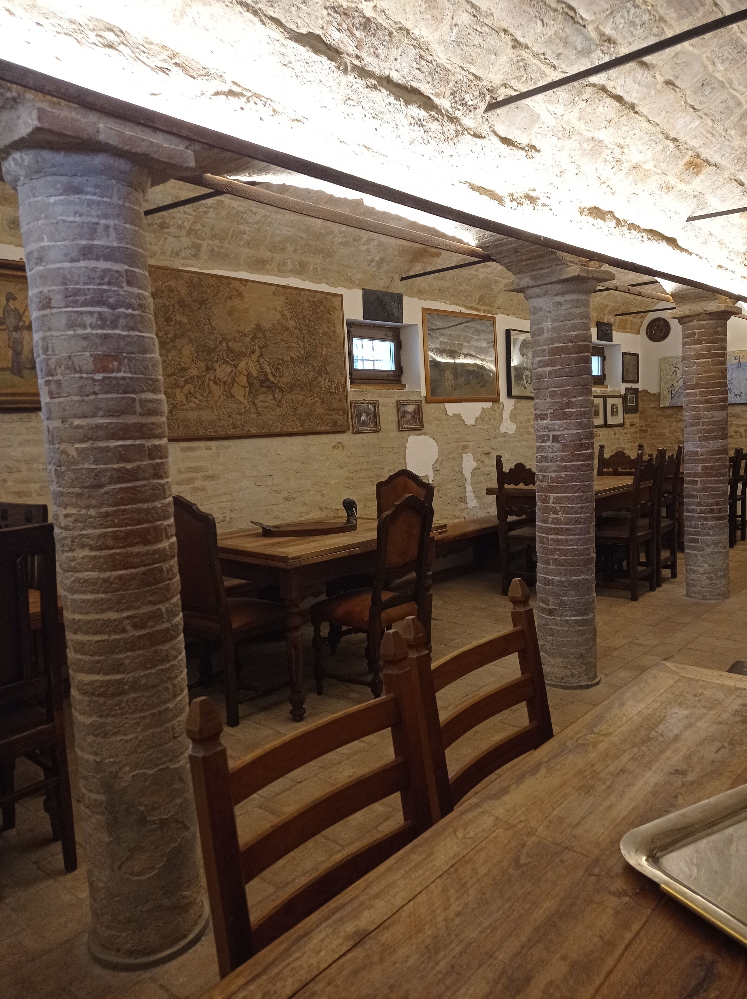 A room with stone pillars, wooden furniture, and artwork on the walls.