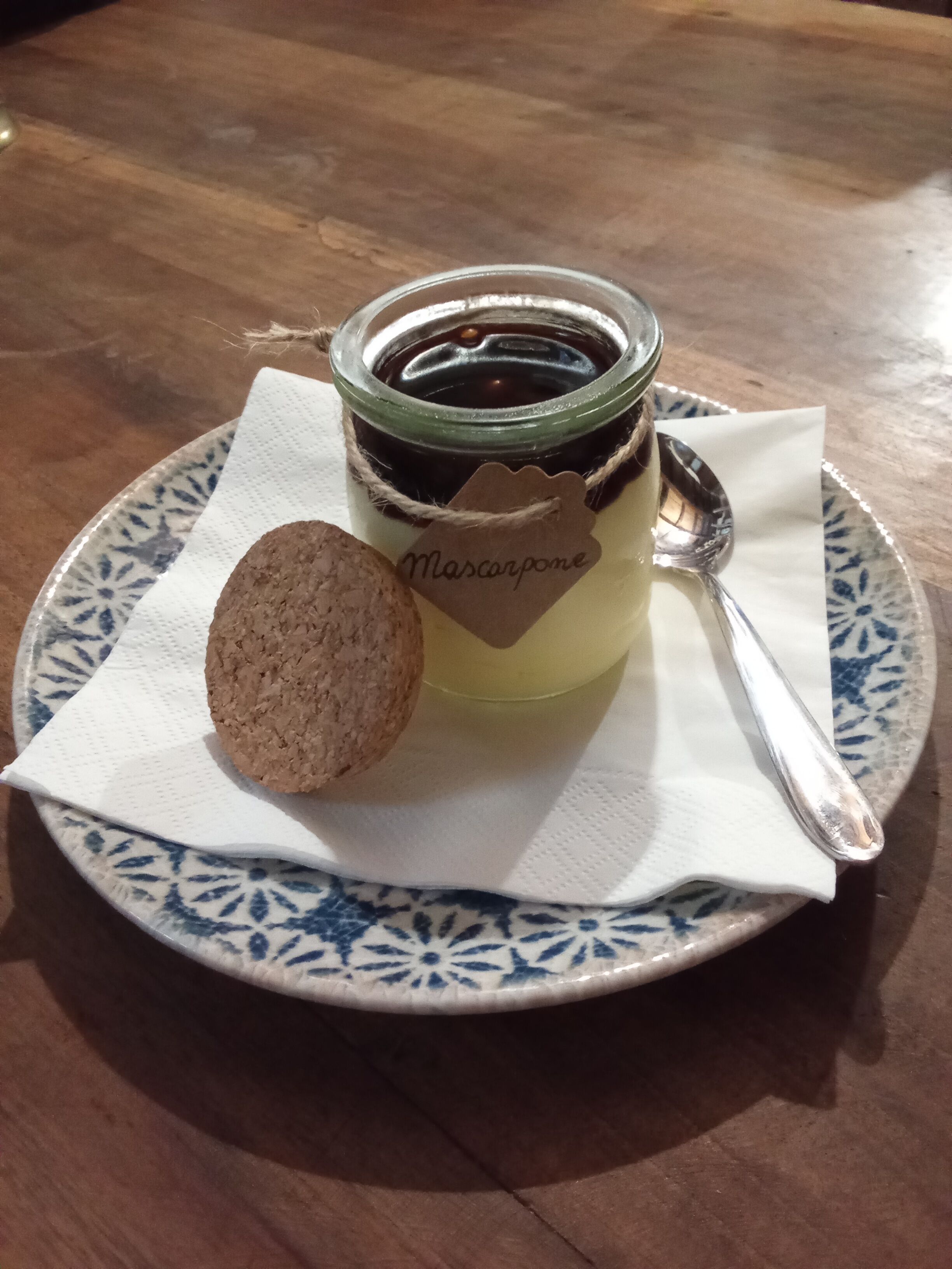 Un recipiente de mascarpone sobre un plato con una cuchara y un corcho.