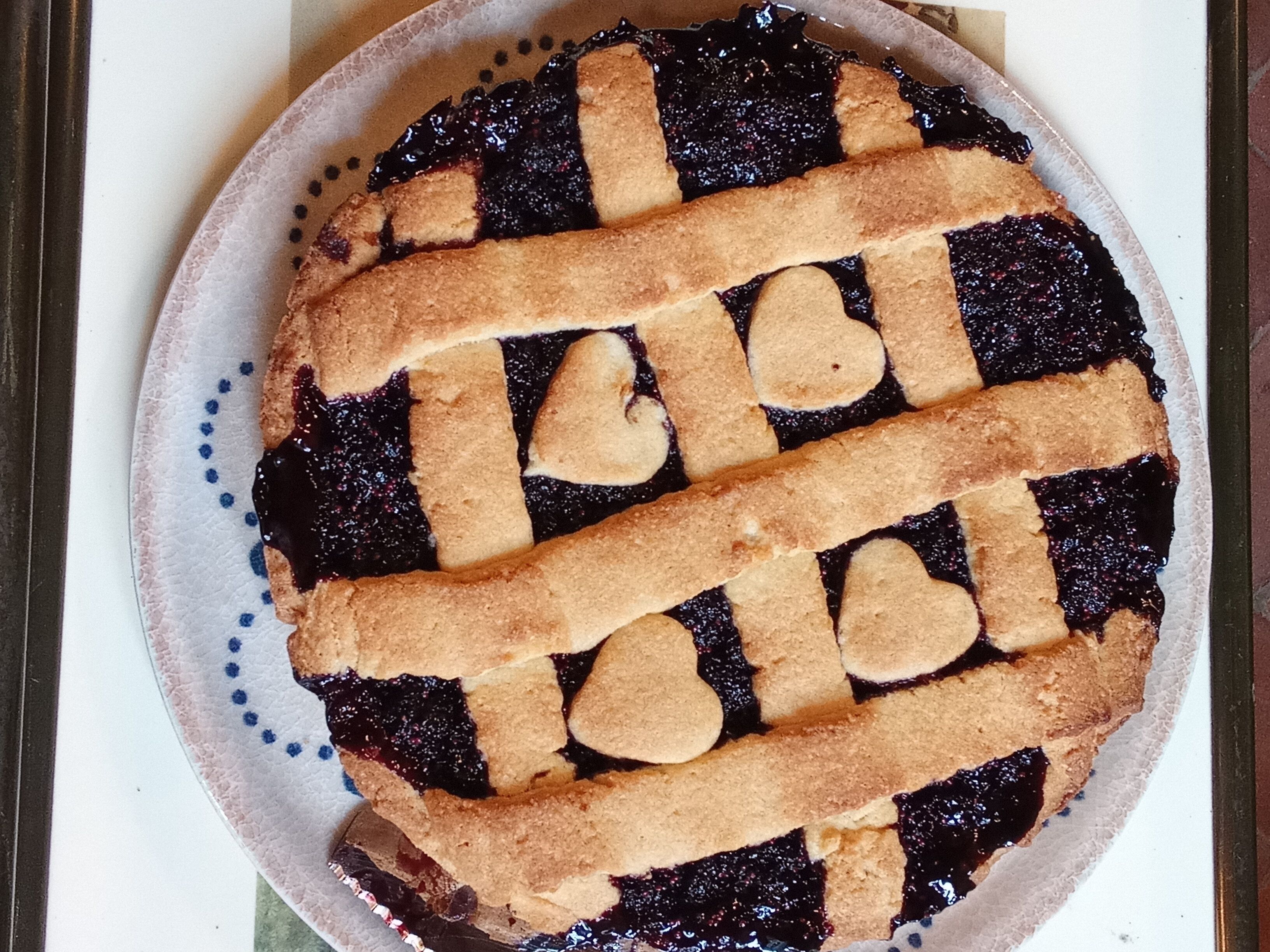 A pie with a lattice crust on a paper plate.