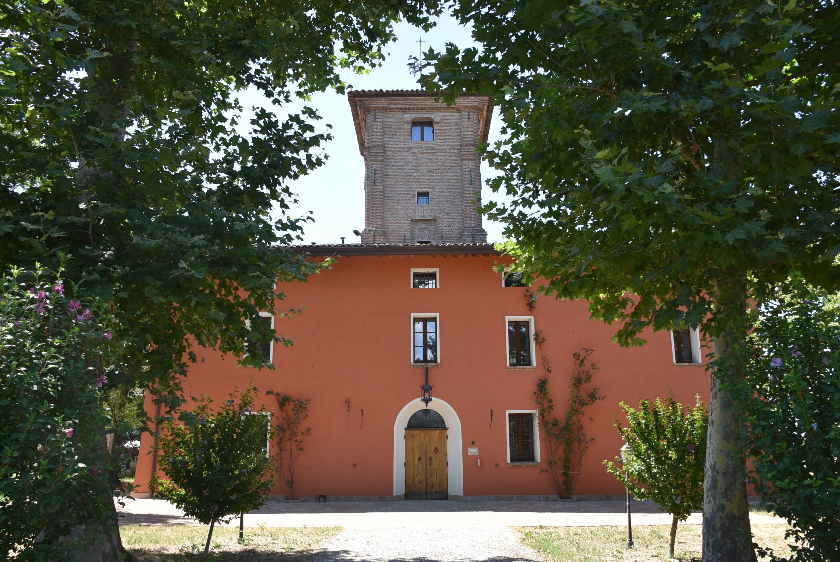 A building with a central tower, a large arched entrance, and a red facade.