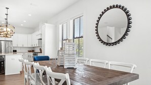 Eine moderne Küche mit weißen Schränken, einem Holztisch und einem großen Spiegel mit dekorativem Rahmen.