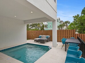 Uma área de piscina com espaço de estar integrado e uma mesa com cadeiras.