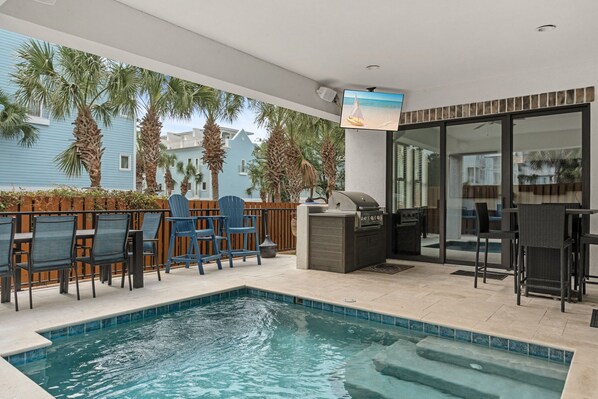 A poolside area with chairs, a grill, and a TV screen. - Brand New Luxury home, Free Beach Chair Service, Private Pool, Perfect Location (Santa Rosa Beach)