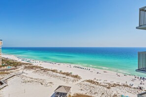 A beach with clear turquoise waters, a sandy shore, and a building with a balcony overlooking the beach. - Beach Front, Water Views, 3 Pools, Beach Bar (Destin)