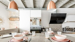 Una cocina moderna con dos lámparas colgantes, un protector contra salpicaduras de ladrillo y un televisor grande.