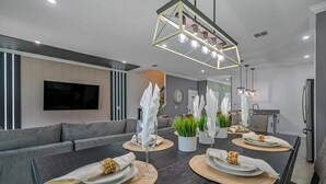 Zona pranzo moderna con un tavolo lungo, finitura in legno scuro e lampada a sospensione geometrica.