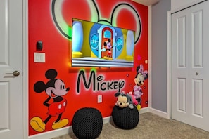 A room with a Mickey Mouse mural, a television, and two black bean bag chairs. - Luxury, Corner Lot, Pond View Vacation Home (Kissimmee)