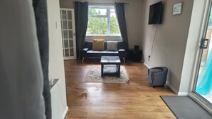 A living room with a sofa, a coffee table, and a TV mounted on the wall. - Beautiful 3-bed House in Ramsgate (Ramsgate)