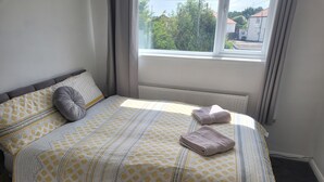 A neatly made bed with a patterned bedspread, pillows, and folded towels. - Beautiful 3-bed House in Ramsgate (Ramsgate)