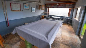 A room with a bed, a table, and chairs. There are pictures on the wall, a window, and a door.