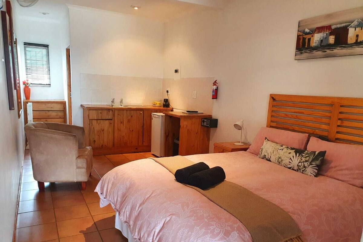 A bedroom with a bed, a desk, and a chair.