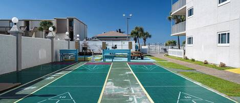 Ein Innenhof mit Shuffleboardfeld, Bänken und einem kleinen Poolbereich.