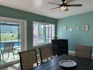 A dining area with a table, chairs, and a view of a swimming pool.