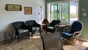 Ein Zimmer mit Korbmöbeln, einem kleinen Tisch und einem Fenster mit Blick.