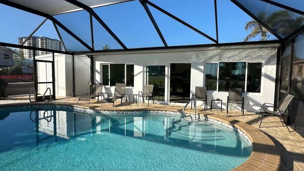 Ein Schwimmbad mit Glasveranda, Liegestühlen und blauem Himmel.