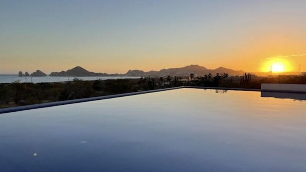 Ein freier Blick auf ein Infinity-Pool mit Sonnenuntergang im Hintergrund.