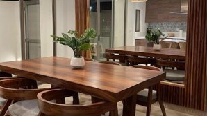 Ein moderner Essbereich mit Holztisch und -stühlen, Pendelleuchten und Blick in die Küche im Hintergrund.
