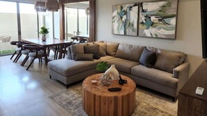 Ein modernes Wohnzimmer mit einer Eckcouch, einem Holztisch und abstrakter Kunst an der Wand.