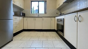 A kitchen with beige cabinets, a stainless steel refrigerator, a microwave, a sink, and an oven. - Sydney Two-Level 3BDR 3BATH near CBD & Olympic Park  (Burwood)