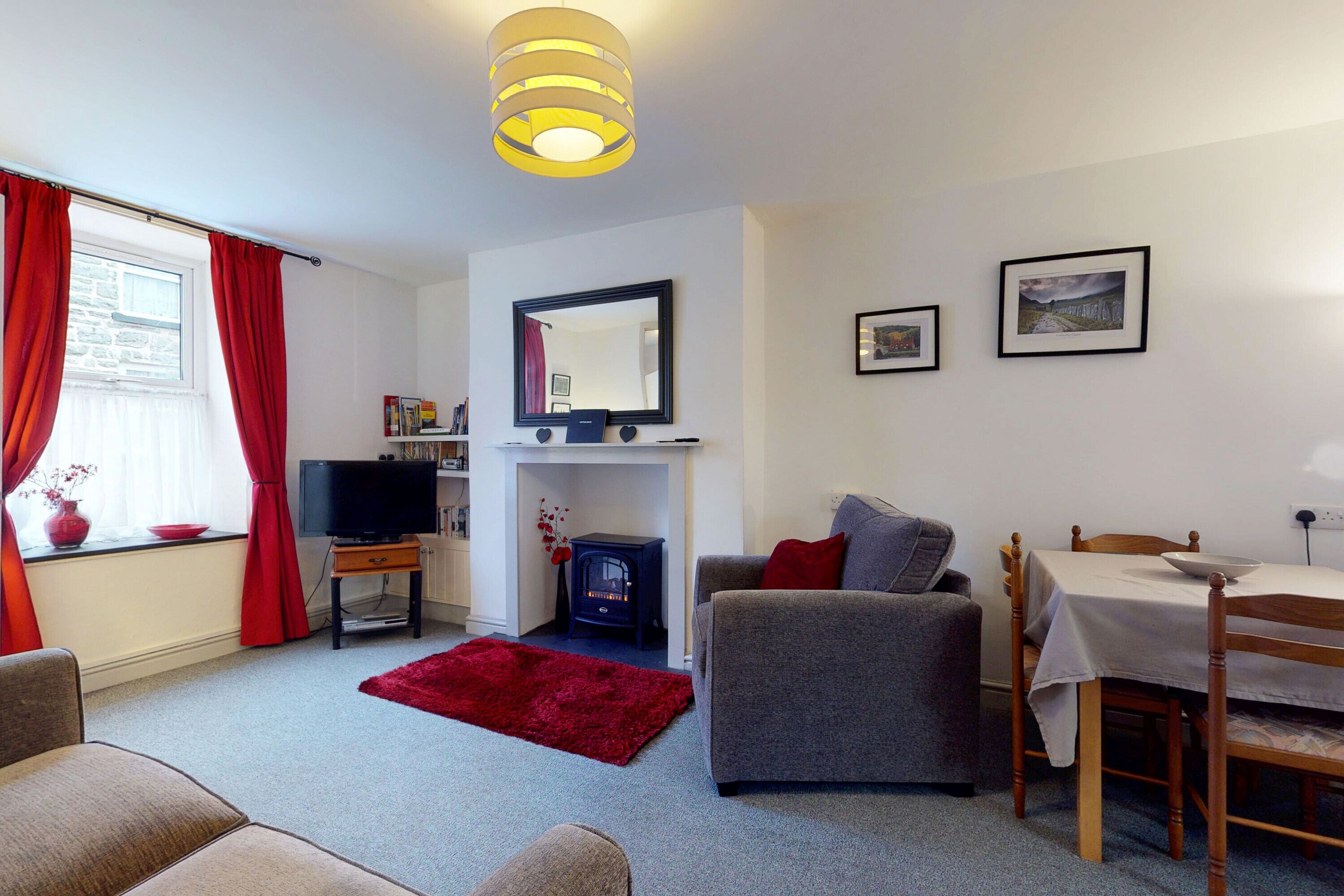 A cozy living room with a fireplace, a television, a dining table, and a sofa.